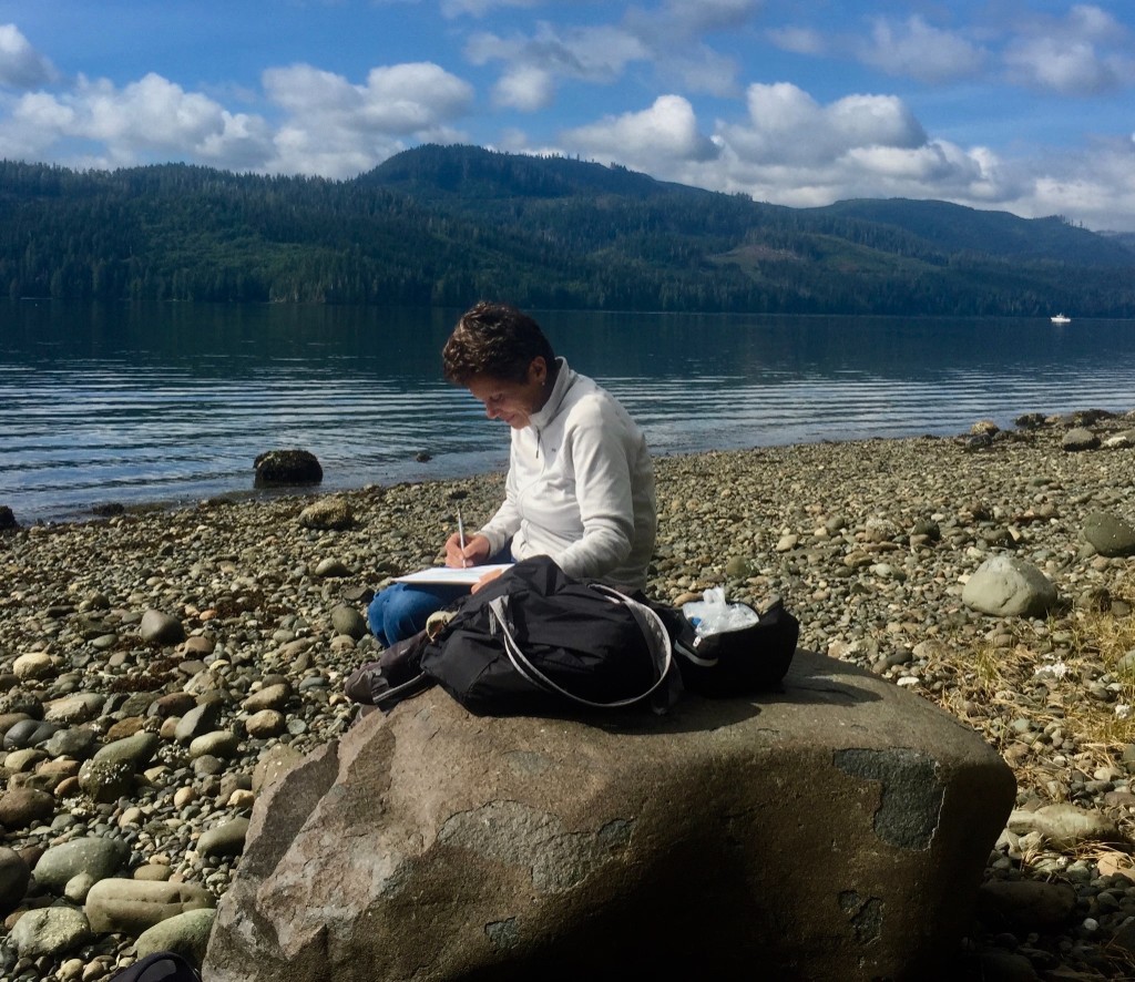 Patrizia Della Bella mentre disegna appunti all’aperto, tra lago e montagne